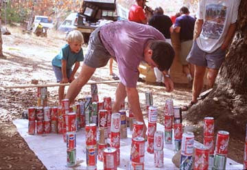 A caver carefully navigates obstacles created from soda cans, simulating an in-cave experience.